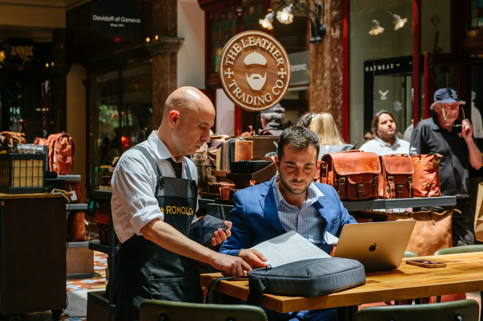 Shop owner and customer reviewing property papers at a Sydney cafe