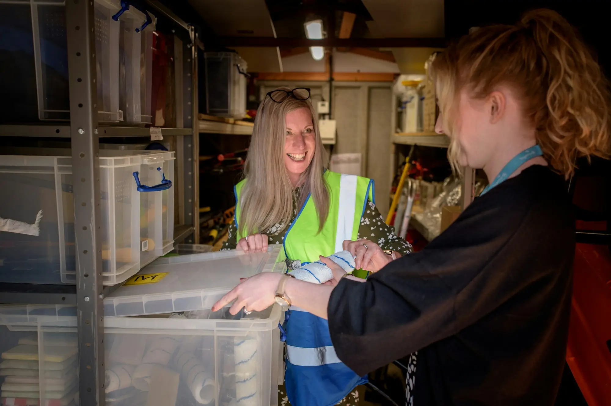 Warehouse staff checking stock in plastic tubs on the shelves